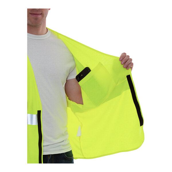 A man holding a Tingley Hi-Vis lime yellow safety vest with black pockets.