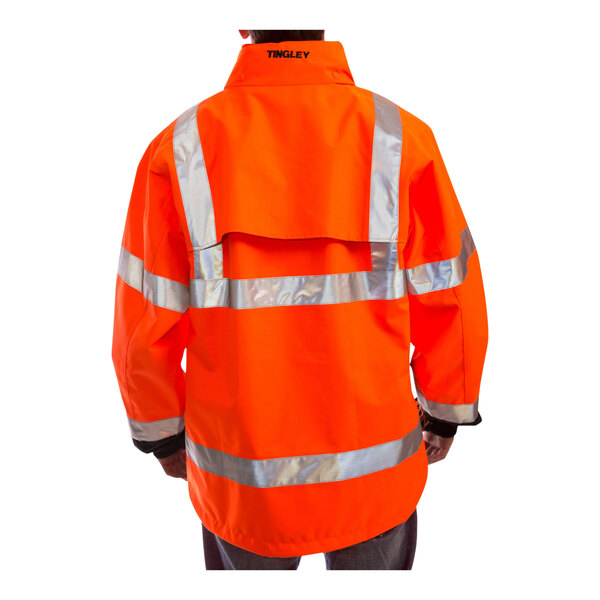 A person wearing a Tingley hi-vis orange jacket with black panels and reflective stripes.