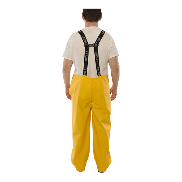 A man wearing Tingley yellow rain overalls with suspenders.
