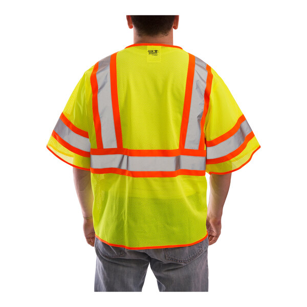 A man wearing a Tingley yellow mesh safety vest with reflective stripes.