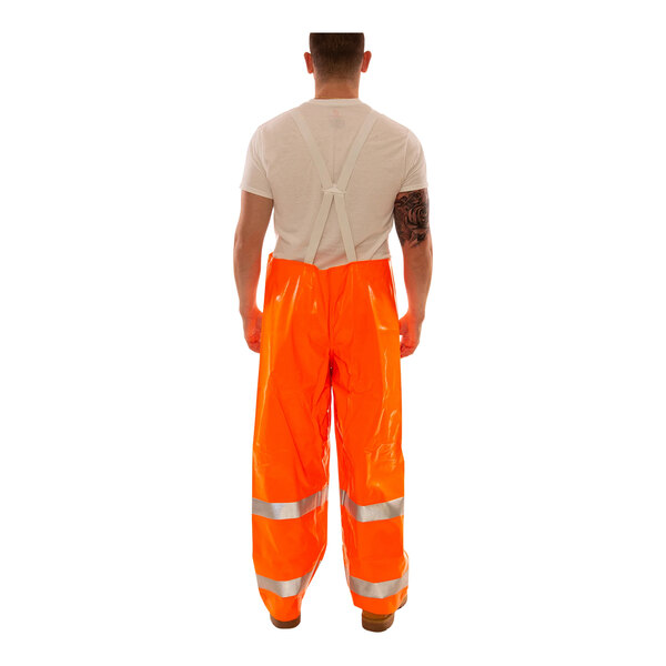 A person wearing Tingley Comfort-Brite orange rain overalls.