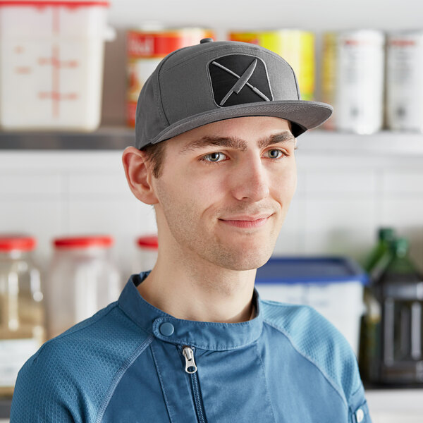 A smiling man wearing a Mercer Culinary gray 5 panel cap with a black and white logo patch.