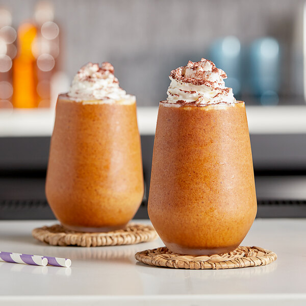 Two glasses of brown Kelvin Slush Co. frozen coffee drinks with whipped cream on top.