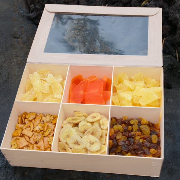 A VerTerra paper take-out box with 6 compartments of assorted dried fruits, including pineapple, raisins, and bananas.