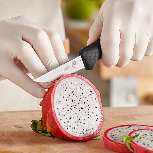 A person using a Mercer Culinary paring knife to cut a dragon fruit.