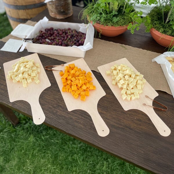 A table with different types of cheese on VerTerra rectangular cheese boards.