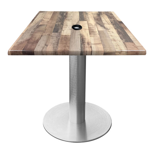 A Holland Bar Stool EnduroTop table with a wood surface and metal base with a metal pole for an umbrella.