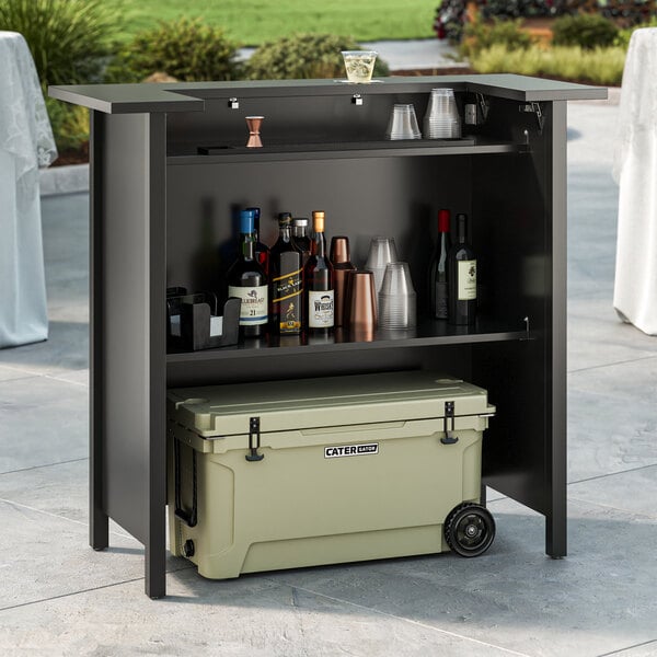 A Lancaster Table and Seating portable bar with bottles and cups on top of it.