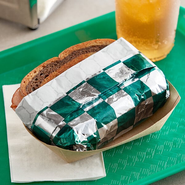 A sandwich in a green and silver Bagcraft paper wrapper.