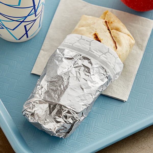 A burrito wrapped in Bagcraft silver honeycomb foil on a tray.