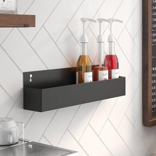 A Steelton black single tier speed rail with bottles of liquid on it.