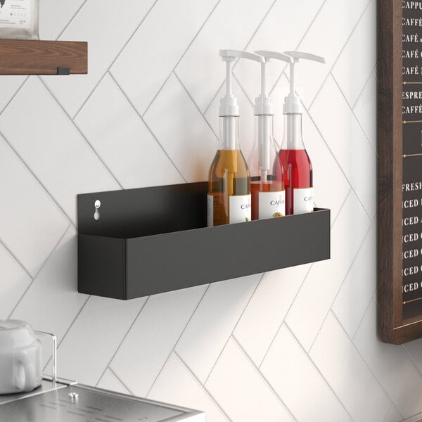 A black Steelton single tier speed rail shelf holding bottles of liquid.