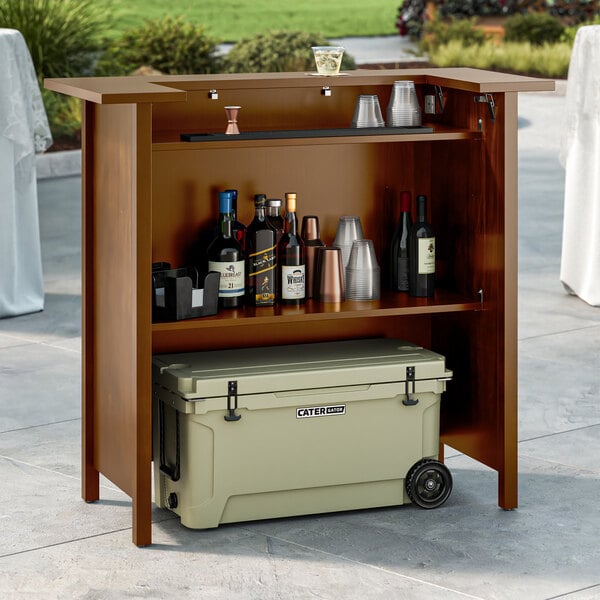 A Lancaster Table and Seating Vineyard Series portable bar with bottles and a cooler on top of it.