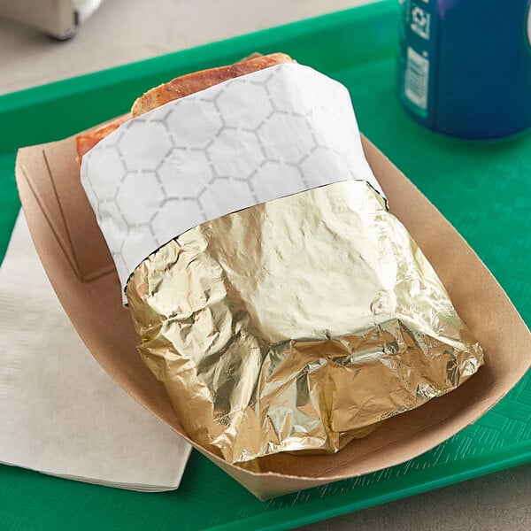 A sandwich in a Bagcraft gold foil wrapper on a tray.