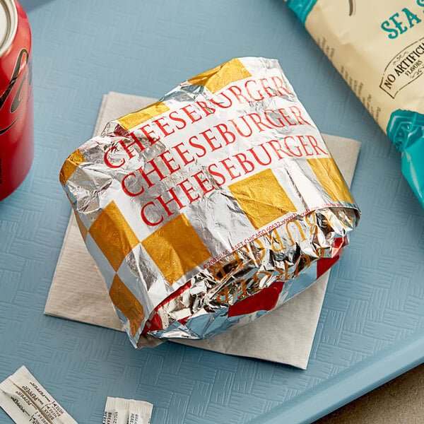 A Bagcraft honeycomb foil wrapped cheeseburger on a tray.