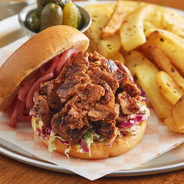 A sandwich with Before the Butcher plant-based pulled pork and fries on a plate.
