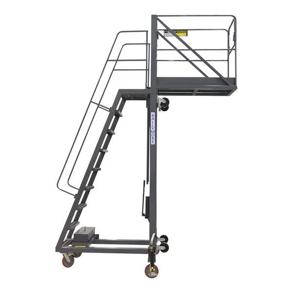 A grey Ballymore steel cantilevered work platform with wheels and a handrail.