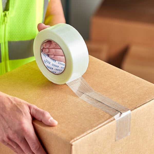 A hand using Lavex clear strapping tape to seal a box.