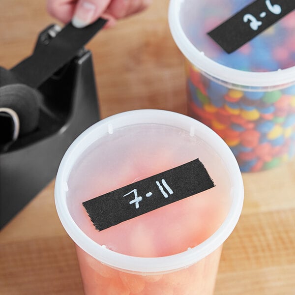 A plastic container of black Lavex masking tape on a counter with other containers of candy.