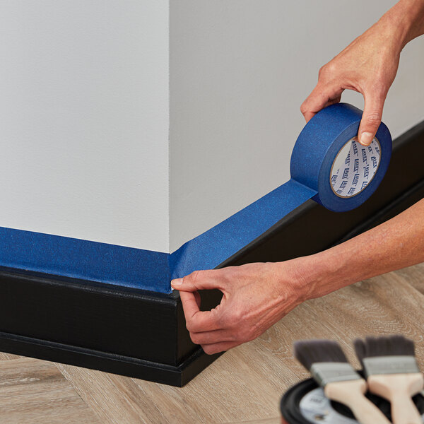 A person's hands holding a roll of Lavex blue painter's tape.