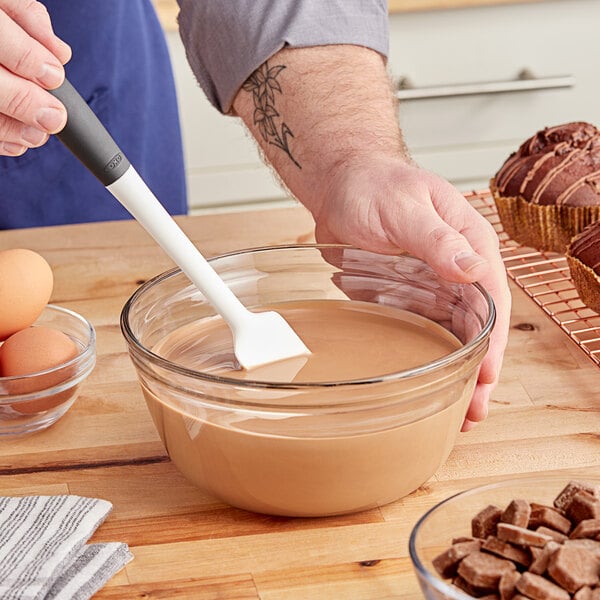 A person using a spatula to mix Lindt milk chocolate with other ingredients in a bowl.