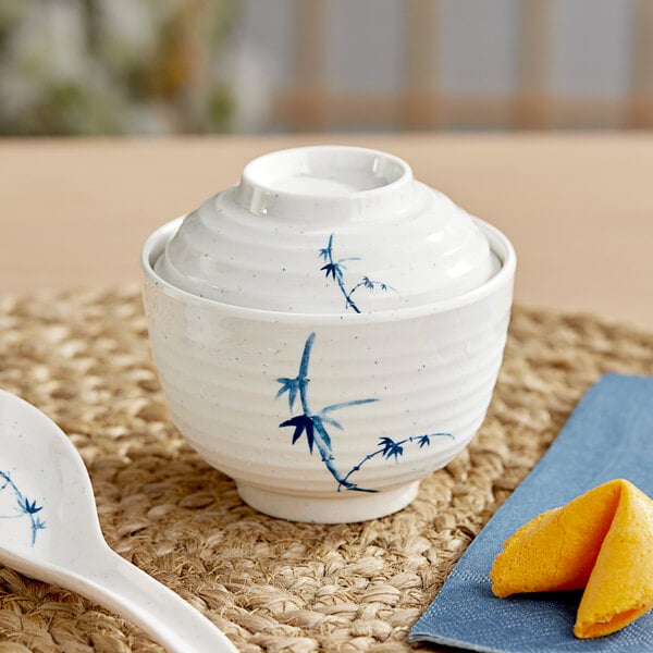 A white Acopa melamine bowl with a lid and a blue spoon.