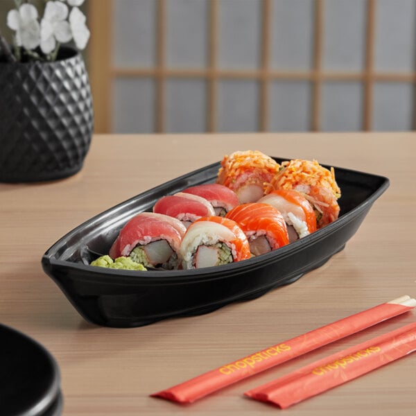 A black melamine sushi boat with sushi on a table.