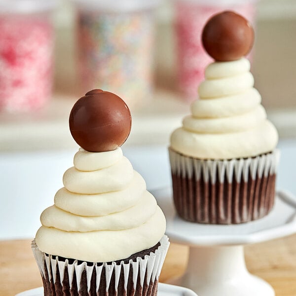 A chocolate ball on top of a chocolate frosted cupcake.