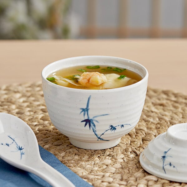 A close-up of a white Acopa Bambu melamine miso bowl filled with soup with a spoon.