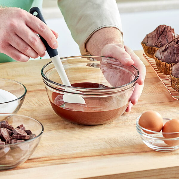 A person stirring Lindt 58% cocoa dark chocolate chips into a bowl of brown liquid.