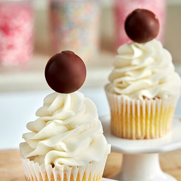 A cupcake with white frosting and a Lindt Lindor dark chocolate truffle on top.