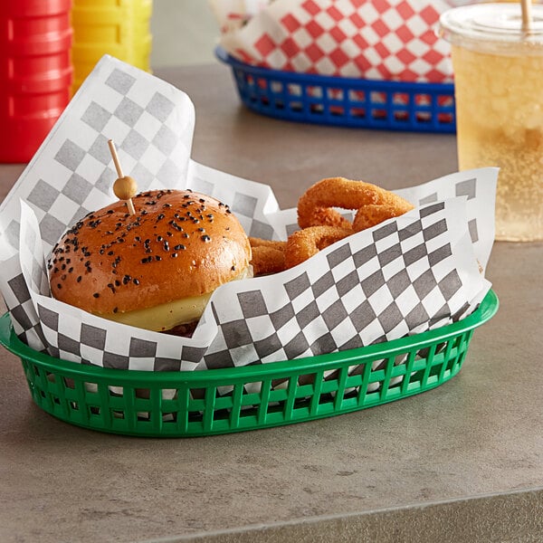 A blue basket with a sandwich wrapped in red and white checkered paper.