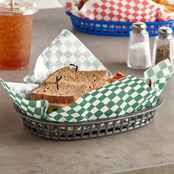 A basket with a Choice small green check deli sandwich wrap paper around a sandwich on a table.