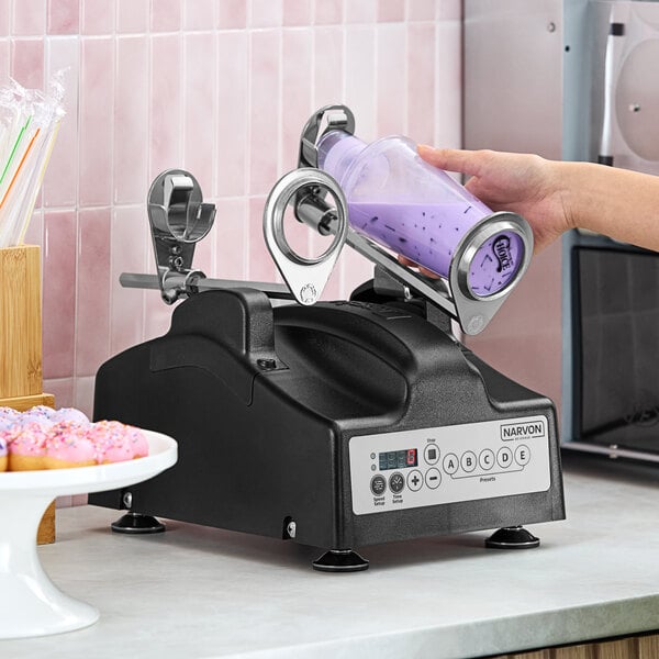 A person using a Narvon bubble tea shaking machine to mix purple liquid.