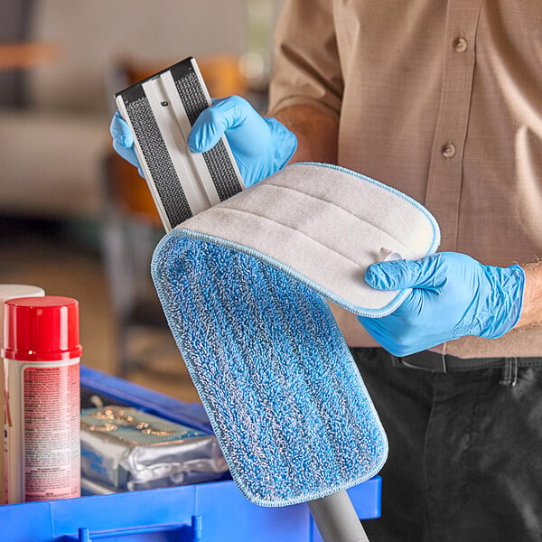 A person holding a blue and white Advantage Supplies microfiber mop pad.