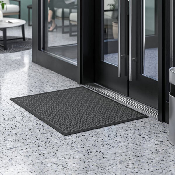 A black Lavex parquet entrance mat on a white marble floor.