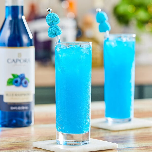 A glass of blue Capora flavoring syrup on a table.