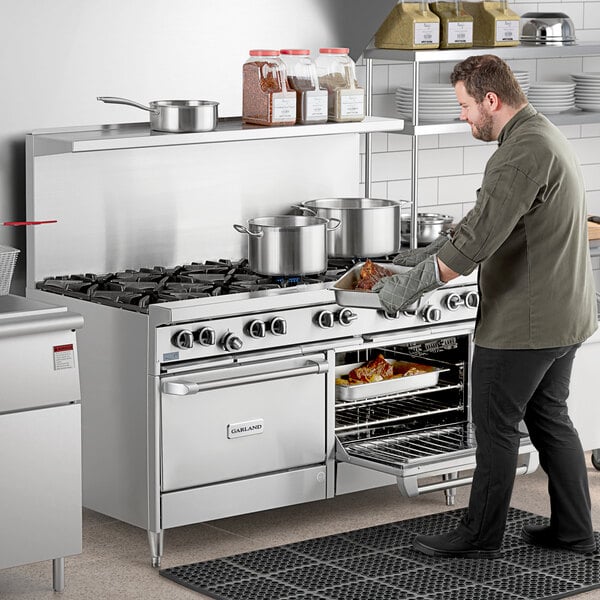 A large stainless steel commercial range with ten burners and two convection ovens, shown in use in a professional kitchen.