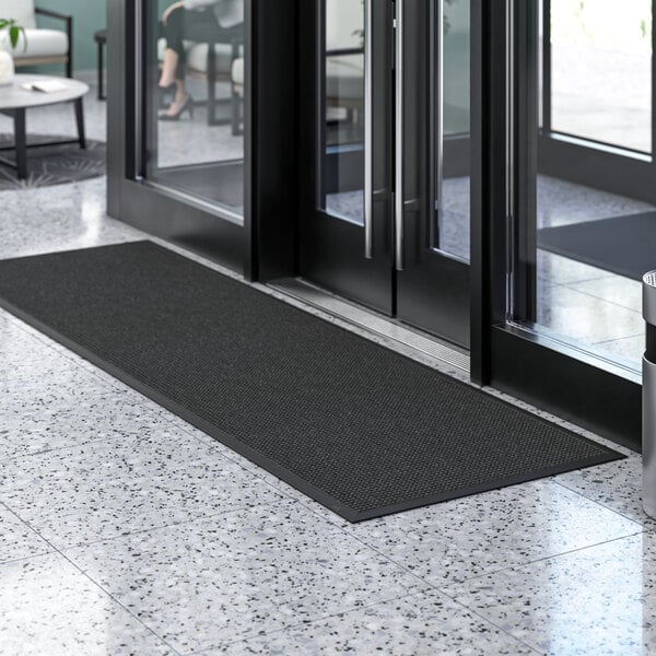 A black Lavex waffle entrance mat on a white tile floor.