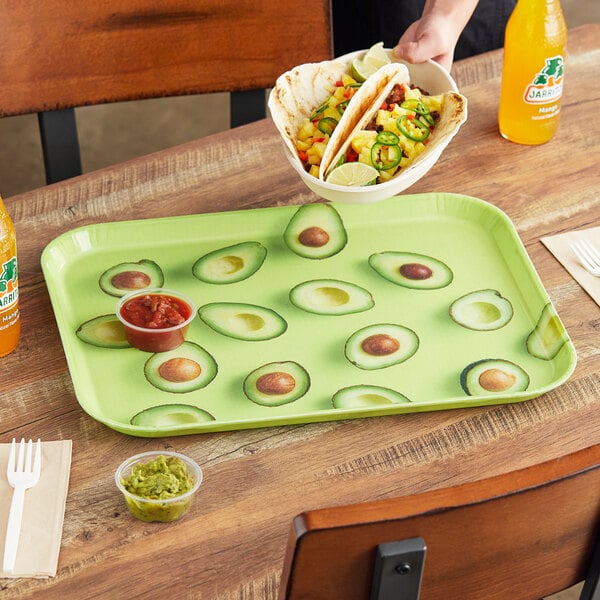 A rectangular Cambro tray with an avocado design holding a taco and a plastic container of guacamole.