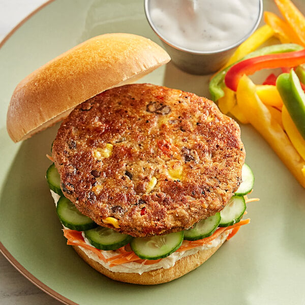 A Dr. Praeger's black bean quinoa veggie burger with vegetables and sauce on a plate.