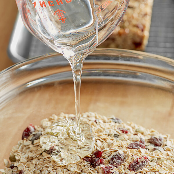 A person pouring Malt Products RiceRite rice syrup into a bowl of oats.