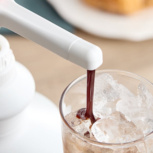 A person pours Capora chocolate flavoring sauce into a glass of ice.