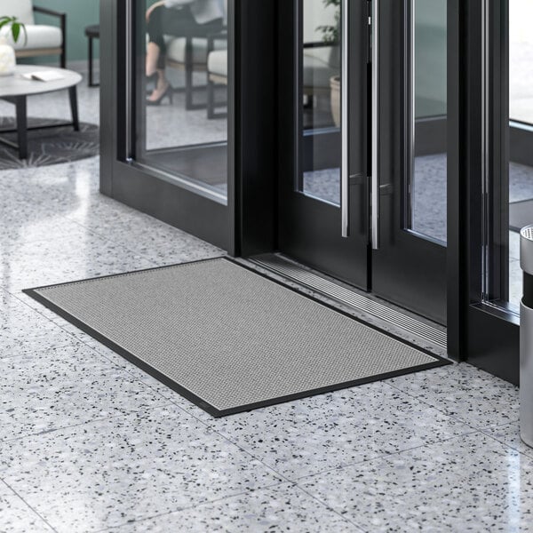 A grey Lavex waffle indoor entrance mat on a marble floor.