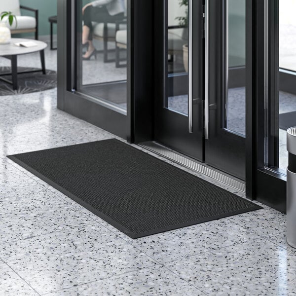 A black Lavex waffle entrance mat on a tile floor.