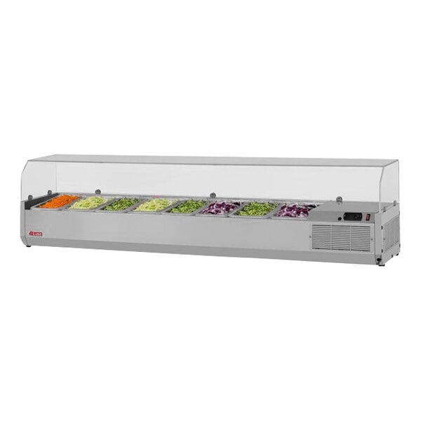 A Turbo Air stainless steel refrigerated countertop salad prep table with clear hood holding containers of vegetables.