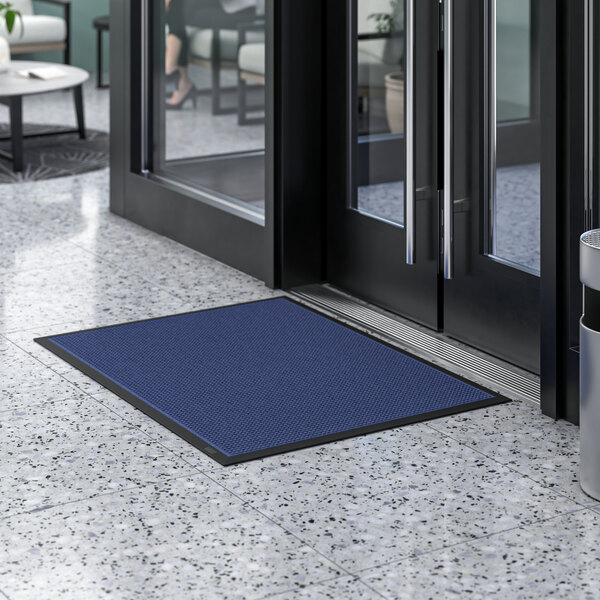 A blue Lavex waffle entrance mat on the floor in front of a door.