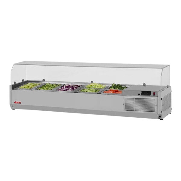 A Turbo Air stainless steel refrigerated countertop salad prep table with clear hood over trays of vegetables.