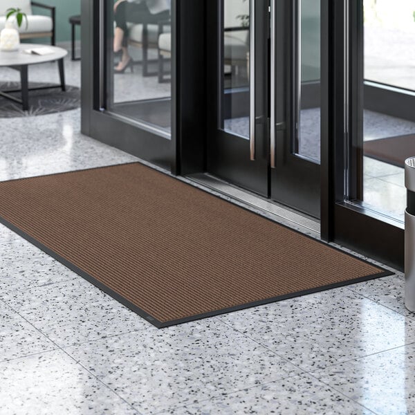 A brown Lavex Needle Rib entrance mat on a white floor.