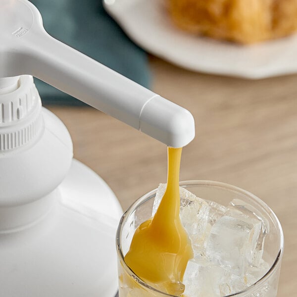A glass with ice and Capora white chocolate flavoring sauce being poured into it.